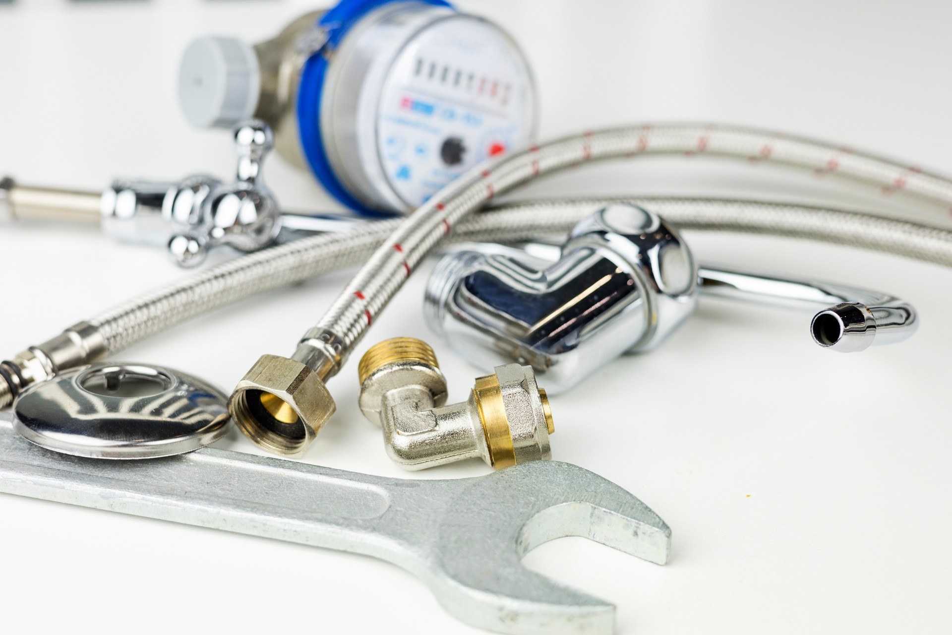 Plumbing parts, accessories and tools on a white background with copy space.